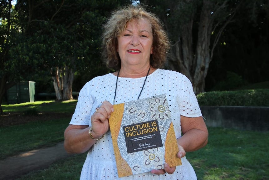 a woman holding a book standing outdoors